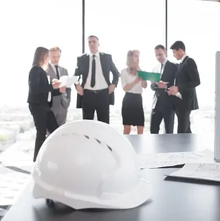 reunion de arquitectos con casco de seguridad y edificio en miniatura en primer plano